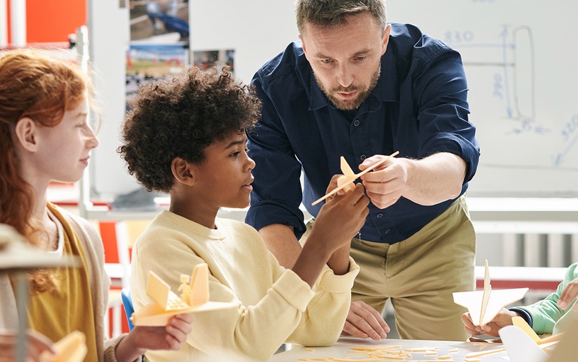 Lehrkraft und Schülerinnen und Schüler betrachten Flugzeugmodelle.
